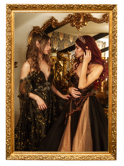 Two fae princesses in dark celestial gowns look at each other in a room with vintage gold decorations.  They are headed to The Paravelle Ball for dancing.